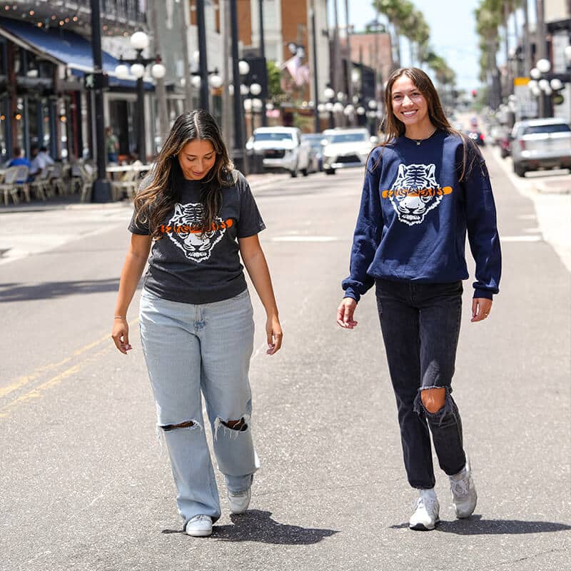 Two women walking on a street wearing branded clothing.