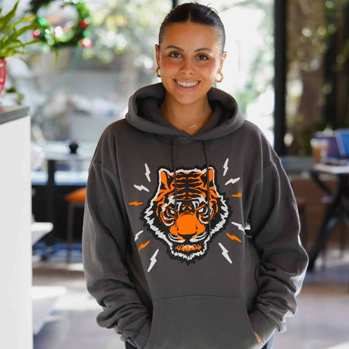 Person wearing a gray hoodie with a tiger graphic in an indoor setting