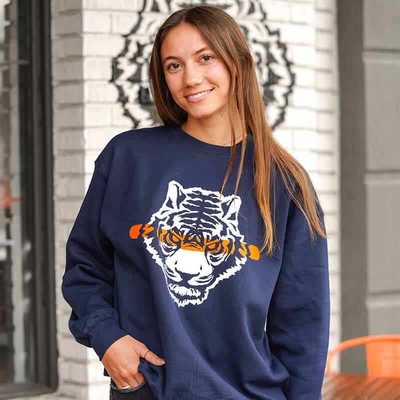 Person wearing a navy blue sweatshirt with a tiger design, standing outdoors.