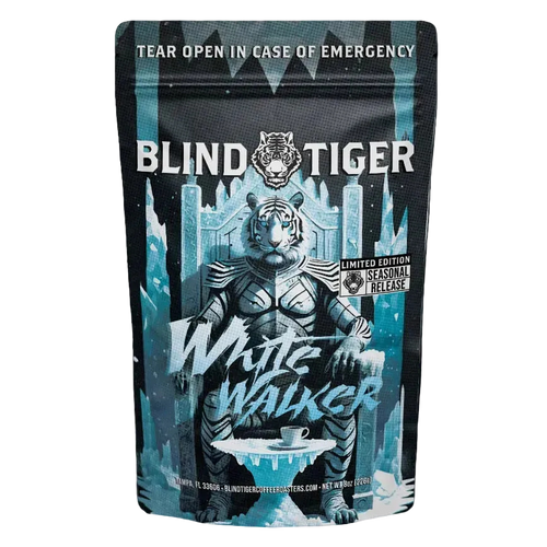 A bag a coffee with a white tiger sitting on a throne of ice with a coffee cup. 